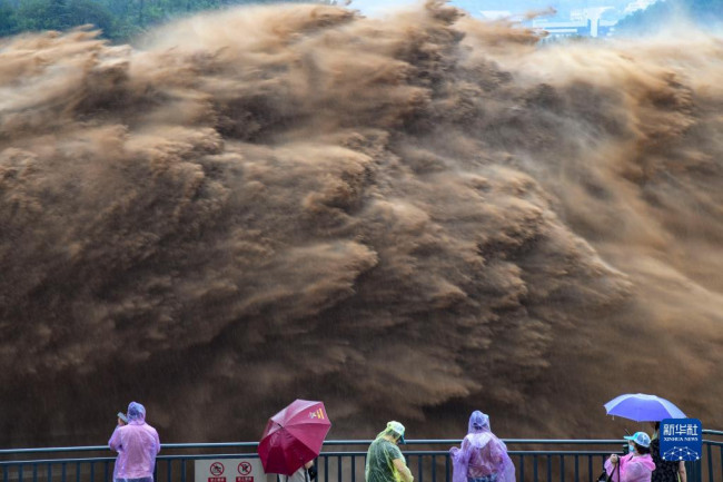 7月19日，游客观看黄河小浪底水库大流量泄洪。