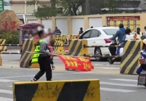 广东一家长怀抱幼儿马路边执勤 当地有关部门回应