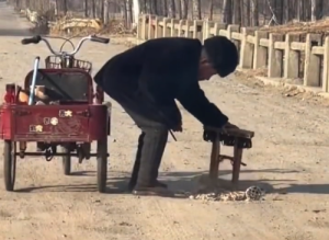 老人颤颤巍巍用煤球渣修补坑洼道路