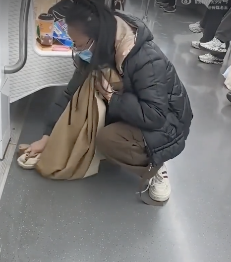 女子在地铁上用围巾擦拭污渍