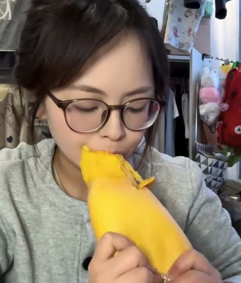 女生吃芒果直接把整个核用嘴拽出来了