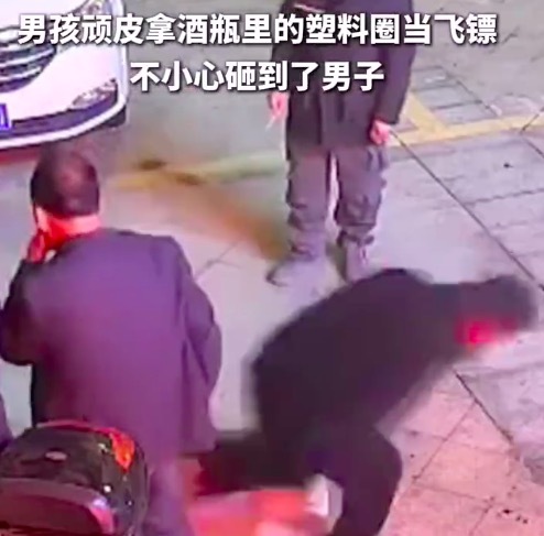男孩拿酒瓶里的塑料圈当飞镖，不慎砸中男子被拖拽着要求道歉