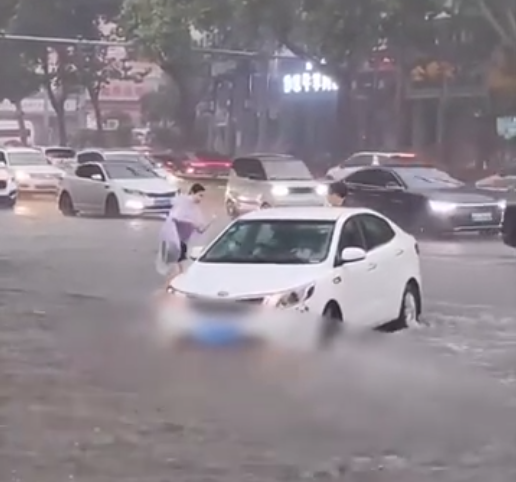 女子骑电动车倒在大雨中被急流冲走 幸遇路人涉水帮扶