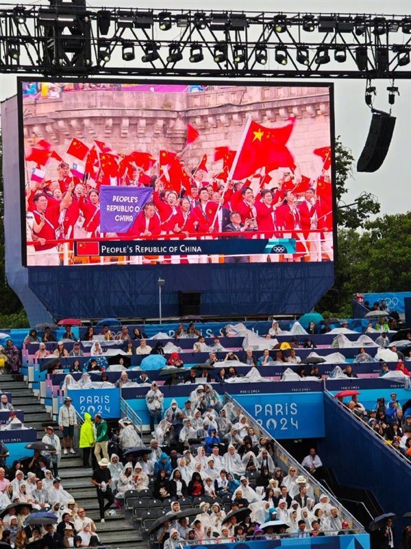 雷军身披雨衣现身巴黎奥运会开幕式 雨中见证历史时刻