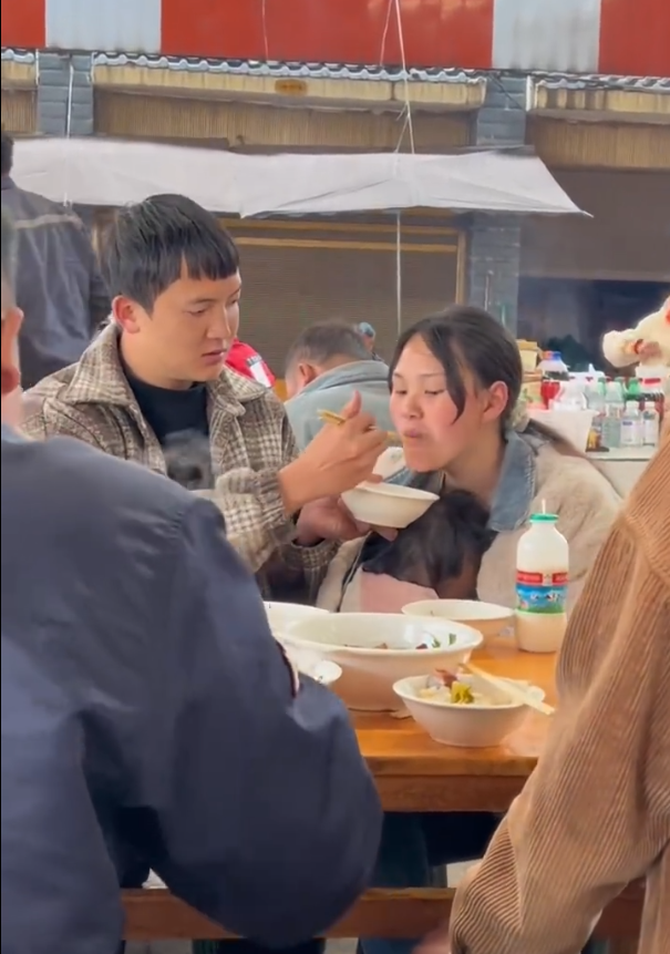 丈夫给抱孩子妻子喂饭