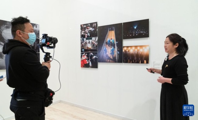 12月28日，在北京首都博物馆举行的第四届全国青年摄影大展上，工作人员在线直播介绍新华社记者肖艺九的摄影作品。