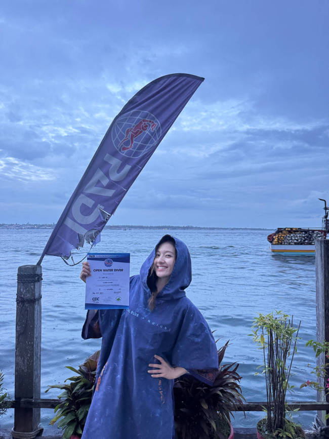 李兰迪拿着潜水证笑容灿烂 坐在海边素颜清秀