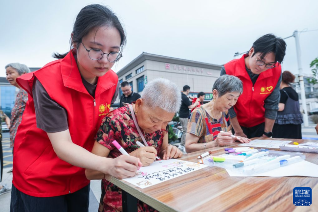 9月20日，在湖州市长兴县雉城街道高家墩居民区，国网湖州供电公司月圆志愿服务队志愿者与街道志愿者陪伴老年居民进行手账绘画，分享日常生活。新华社记者 徐昱 摄
