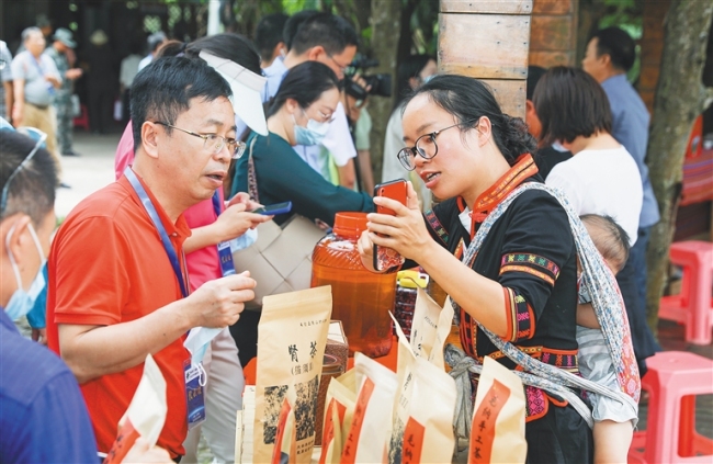 5月18日，毛纳村村民在向游客介绍当地的特色产品。