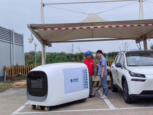 在武汉汉口火车站北广场的国家电网智能充电塔内，国网湖北电力人员正在为新能源汽车车主讲解“智能移动充电机器人”充电的注意事项。沈贤忠摄