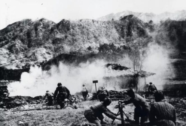 上图_ 长津湖战役中，志愿军用迫击炮向敌人阵地发起攻击，摄于1950 年末
