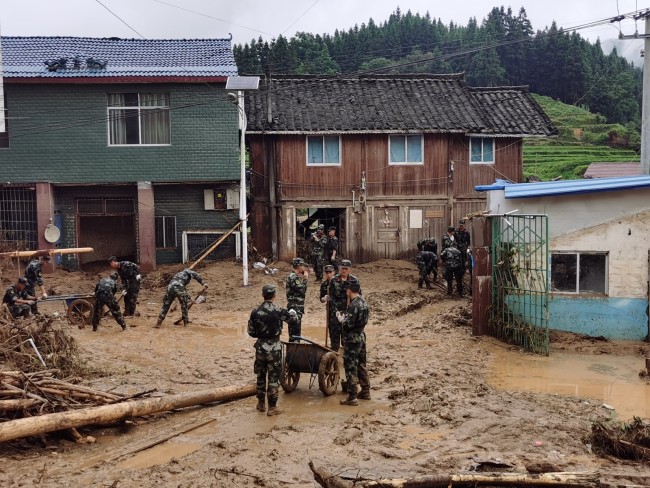 6月20日，武警官兵在受灾群众家中清理淤泥。  侯鲁晋  摄
