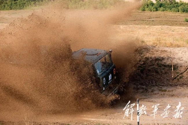 “汽车能手”项目接力赛中，我军参赛队员驾车通过泥坑路段。