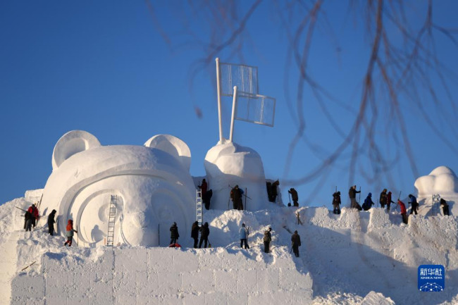 12月24日，在太阳岛雪博会园区，雪雕师在进行本届雪博会主塑的雕刻。