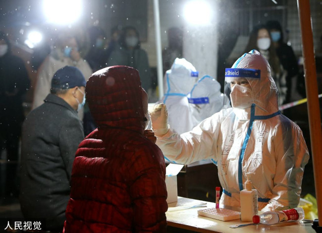 2021年12月25日，西安一社区核酸检测点，雪中医护人员为市民做核酸检测。