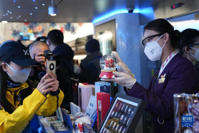 1月6日，在G9981次北京冬奥列车车厢内，一位工作人员在介绍北京冬奥会特许商品。