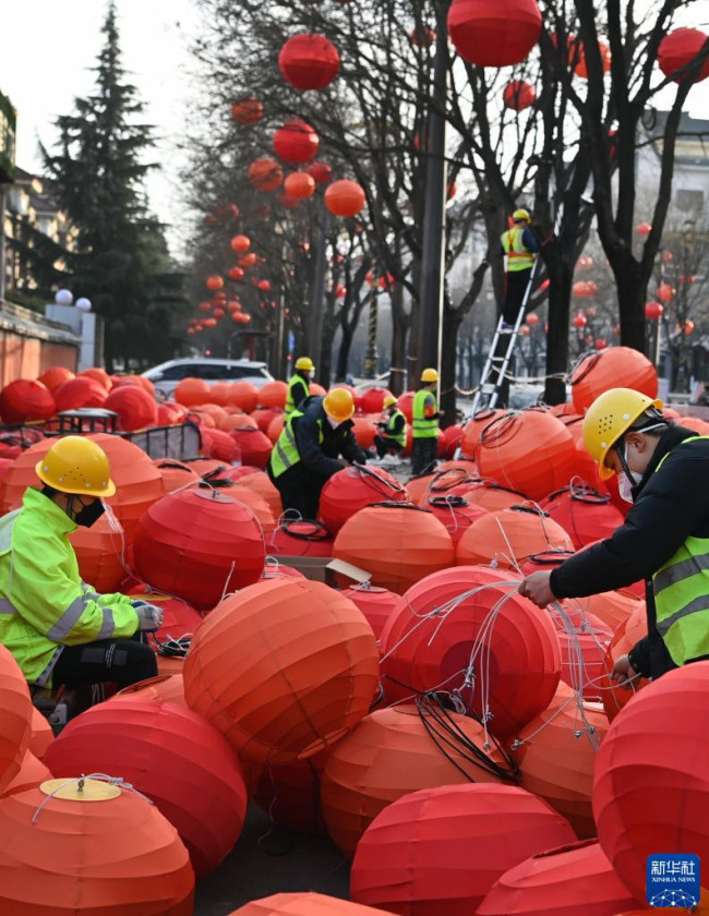 1月15日，施工人员在西安市慈恩东路悬挂红灯笼，迎接春节。