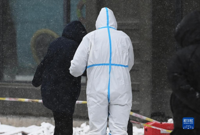 3月15日，在长春市前进大街一个核酸检测点，工作人员搀扶市民在雪中前行。