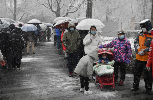 东城封控小区居民开展核酸检测，“大白”贴暖宝大雪中值守