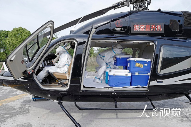 图为工作人员将核酸标本搬运至直升机舱中。