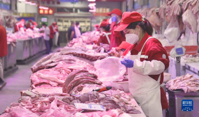 5月20日，新发地市场的肉类批发商户在摊位上工作。