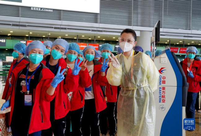 5月23日，在上海虹桥国际机场，一名机场工作人员与医疗队队员合影留念。