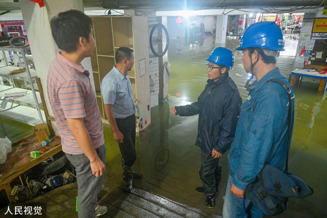 2022年6月20日，江西省婺源县，国网婺源县供电公司电力工人在为被淹的商家解决洪灾时的安全用电问题。
