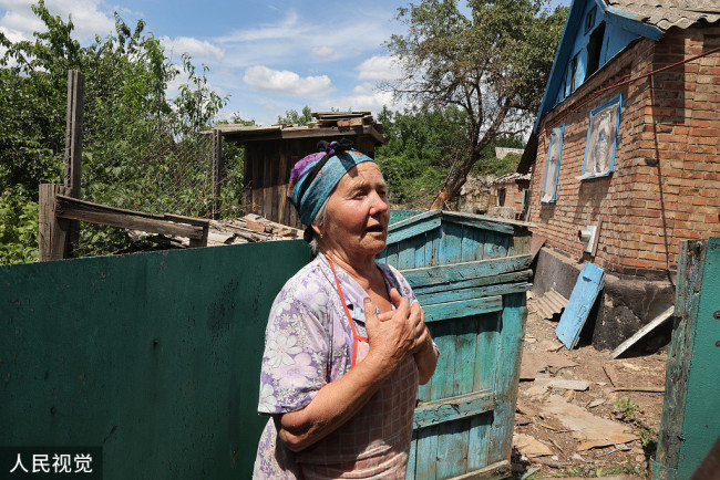84岁的Nadia  Trekun站在被炮火摧毁的房子外，她没有受伤。但她的一名邻居在袭击中丧生，附近几座房屋在炮击中被毁。