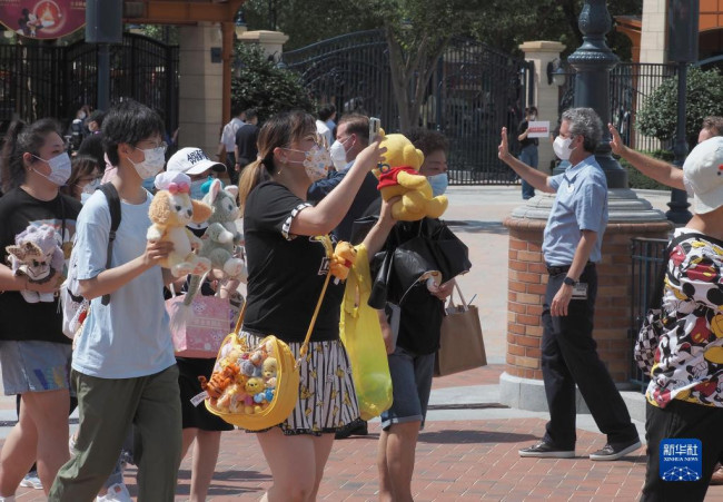6月30日，上海迪士尼工作人員在迪士尼樂園門口歡迎遊客入園。新華社記者 任瓏 攝