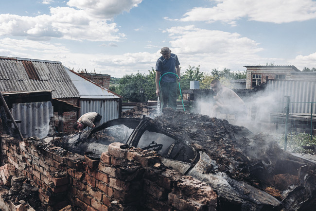 当地时间2022年7月19日，顿涅茨克地区巴赫穆特市，当地遭受炮击后建筑受损严重，居民和消防员在进行灭火。