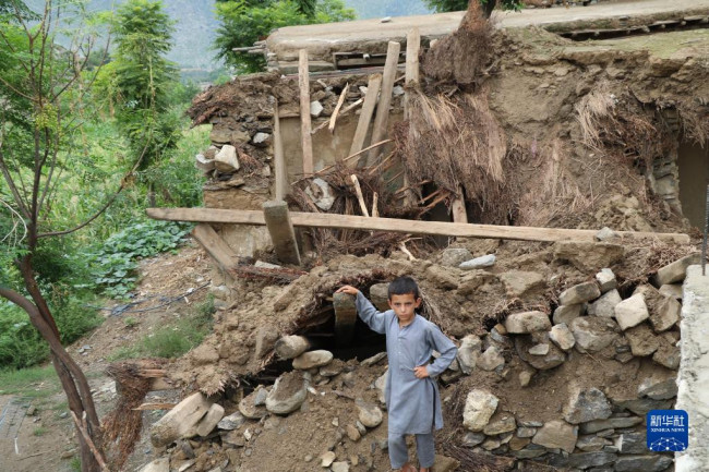 8月18日，一名男孩站在阿富汗努裏斯坦省被洪水損毀的房屋旁。