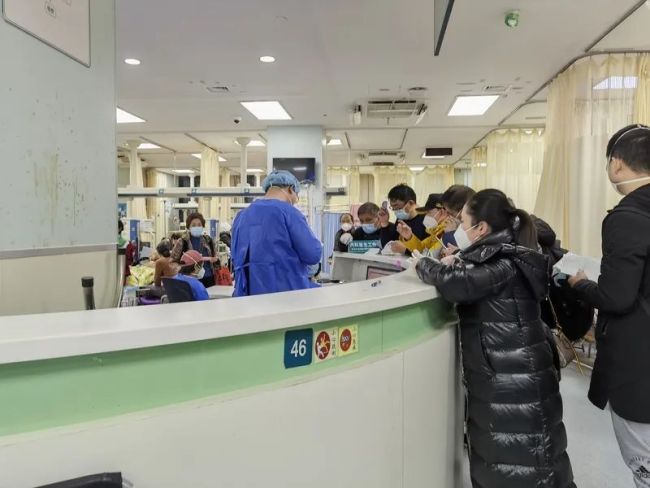 主治医师黄聪华在开医嘱，家属在护士站前排队等待着。林子璐摄