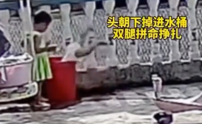 小孩玩水不慎栽进水桶
