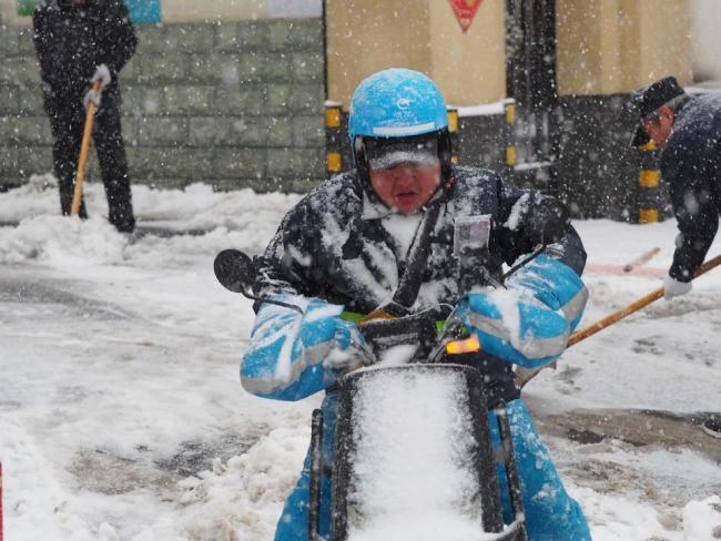 外賣小哥暴雪中緩慢前行送餐 濕滑路面艱難騎行