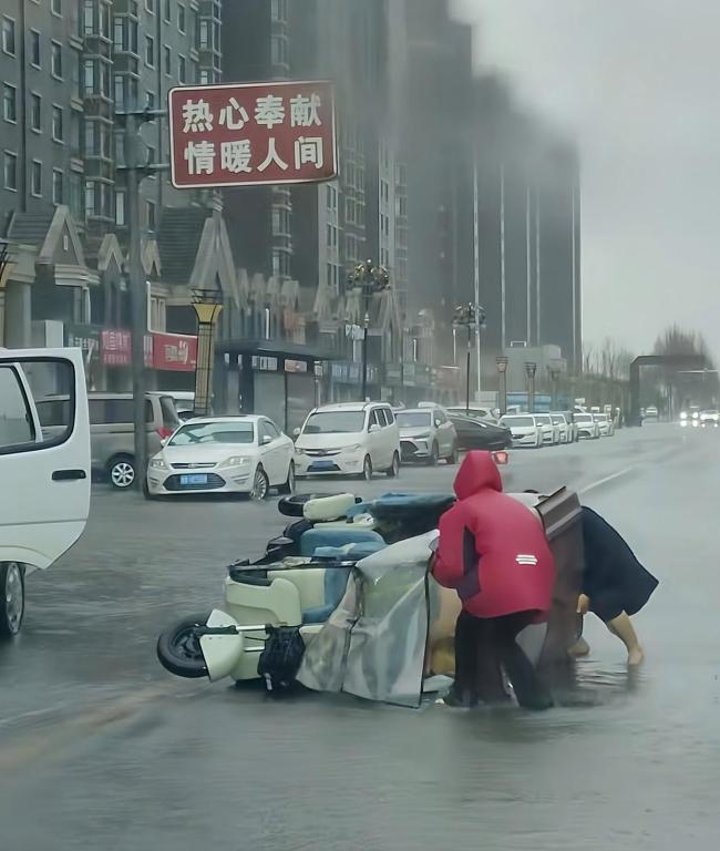 母女騎三輪被風(fēng)刮倒男子幫忙扶車 暴雨中的溫暖援手