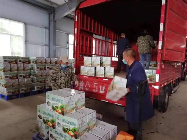 工作人员将采购3000箱的新鲜蔬菜装配上车