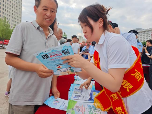 子洲农商行工作人员向群众宣传金融防诈案例