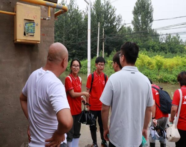实践团成员与村民交流受灾情况。