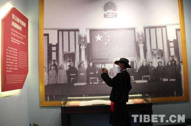 在中国藏学研究中心西藏文化博物馆展出的“丰功伟业——庆祝西藏和平解放70周年特展”，以西藏和平解放70年光辉历程为主线，运用350多幅图片、61件(套)珍贵实物和文献，立体展示出西藏和平解放以来发生的历史性转变、取得的历史性成就。其中，西藏和平解放的历史备受人们关注，图为一名基层干部拍摄相关展板。 摄影：王茜